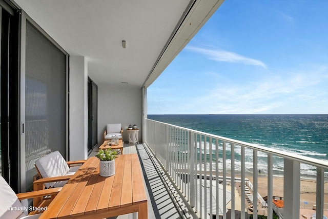 balcony with a water view and a view of the beach