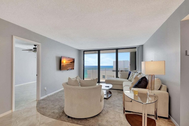 living room with floor to ceiling windows, ceiling fan, light tile patterned flooring, and a textured ceiling