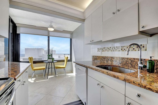 kitchen with white dishwasher, white cabinetry, dark stone counters, and sink