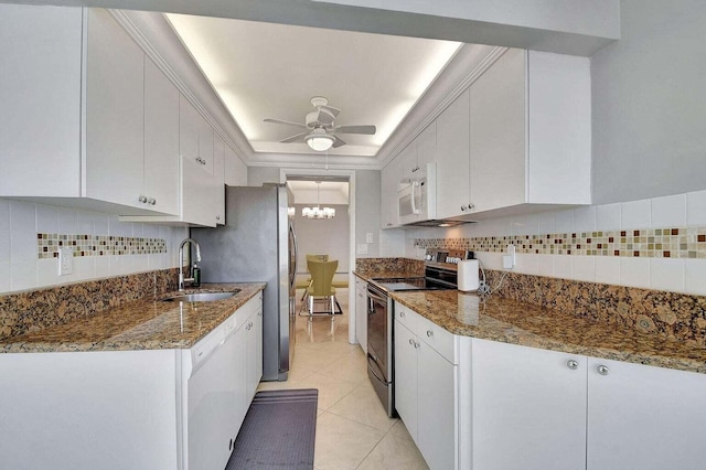 kitchen with ceiling fan with notable chandelier, sink, white cabinets, and white appliances