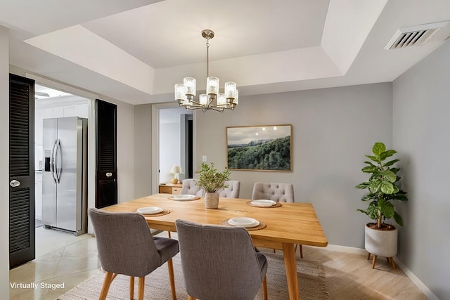 tiled dining room featuring a notable chandelier and a tray ceiling