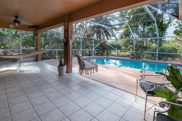 view of swimming pool featuring ceiling fan, a lanai, and a patio