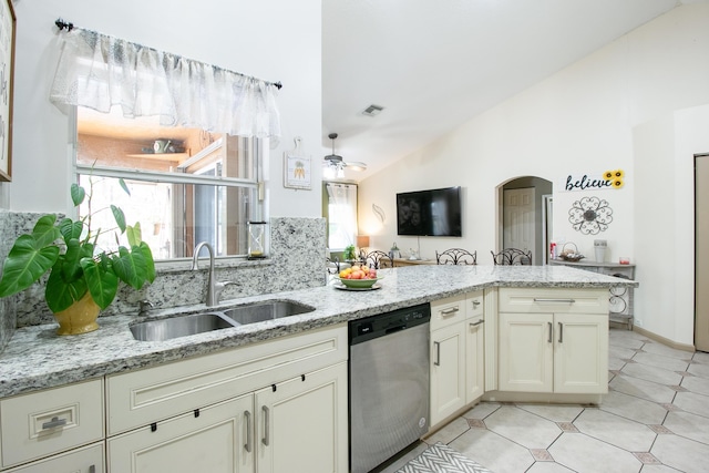 kitchen with vaulted ceiling, light stone counters, stainless steel dishwasher, and sink