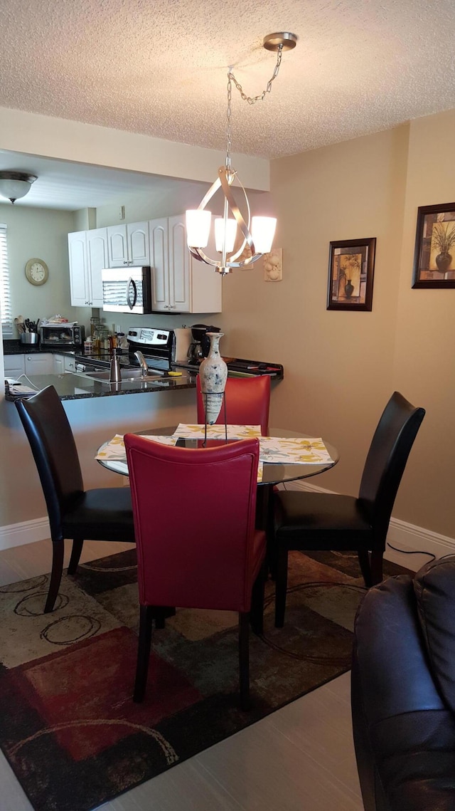 dining room with wood-type flooring, a textured ceiling, and an inviting chandelier