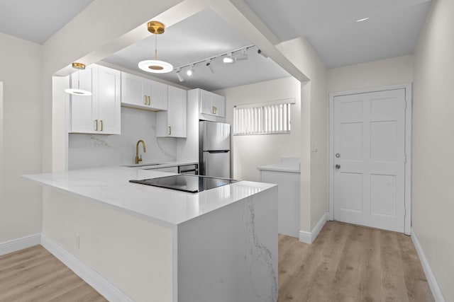 kitchen with stainless steel refrigerator, white cabinetry, kitchen peninsula, light hardwood / wood-style floors, and decorative light fixtures