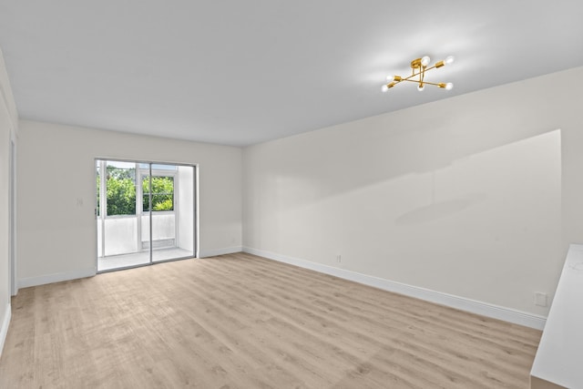 spare room with light hardwood / wood-style floors and an inviting chandelier