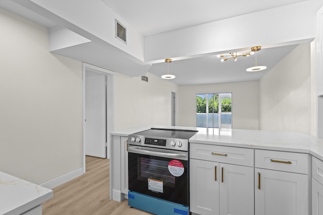 kitchen with electric range, pendant lighting, light stone counters, and light wood-type flooring