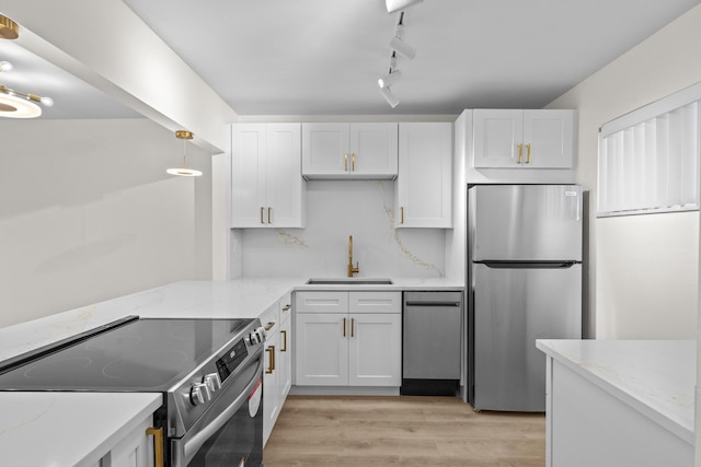 kitchen with hanging light fixtures, sink, light wood-type flooring, white cabinetry, and stainless steel appliances