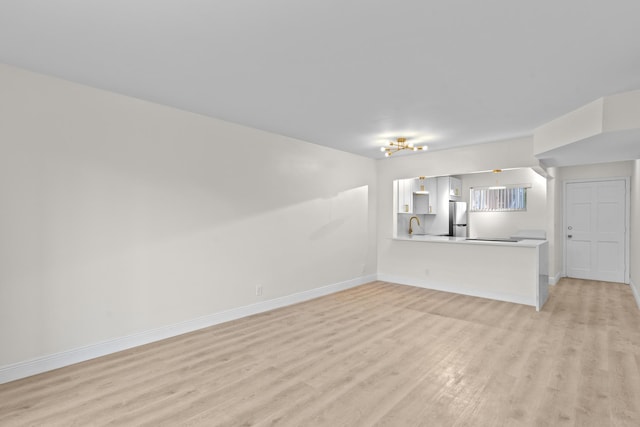 unfurnished living room featuring sink and light hardwood / wood-style floors