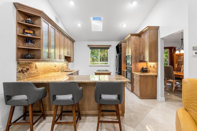 kitchen featuring a breakfast bar, backsplash, sink, vaulted ceiling, and kitchen peninsula