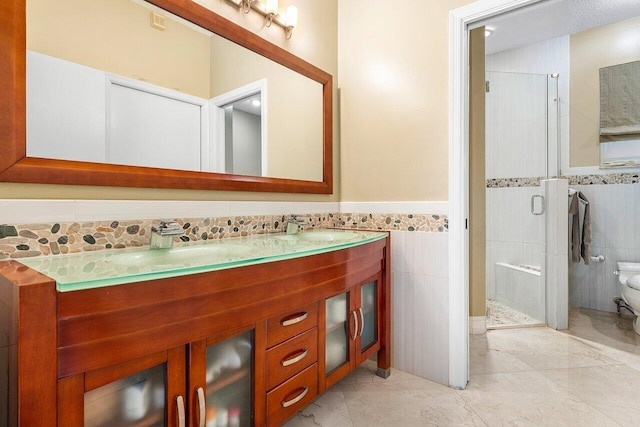 bathroom with vanity, a shower with door, and tile walls