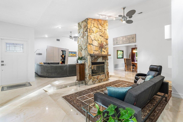 living room featuring a textured ceiling, a stone fireplace, a wealth of natural light, and ceiling fan