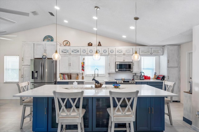 kitchen featuring a wealth of natural light, a large island, a kitchen breakfast bar, decorative light fixtures, and appliances with stainless steel finishes