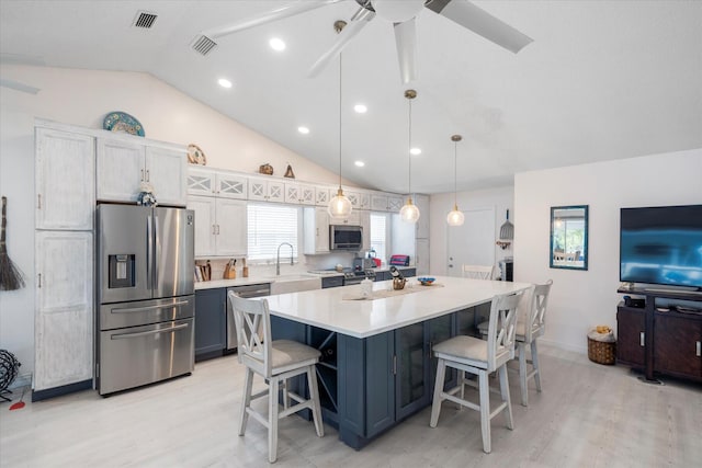 kitchen with lofted ceiling, a kitchen breakfast bar, decorative light fixtures, white cabinetry, and stainless steel appliances