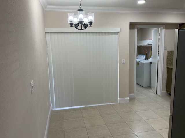 interior space with a chandelier, light tile patterned floors, washer and dryer, and ornamental molding