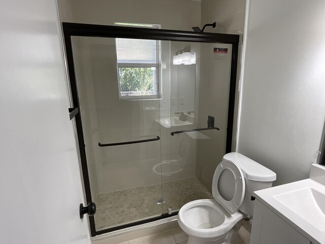 bathroom featuring tile patterned floors, vanity, toilet, and walk in shower