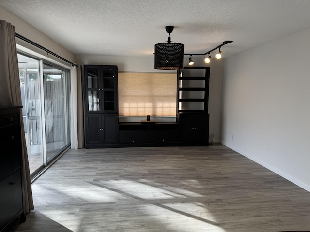 unfurnished living room with hardwood / wood-style floors, rail lighting, and a textured ceiling