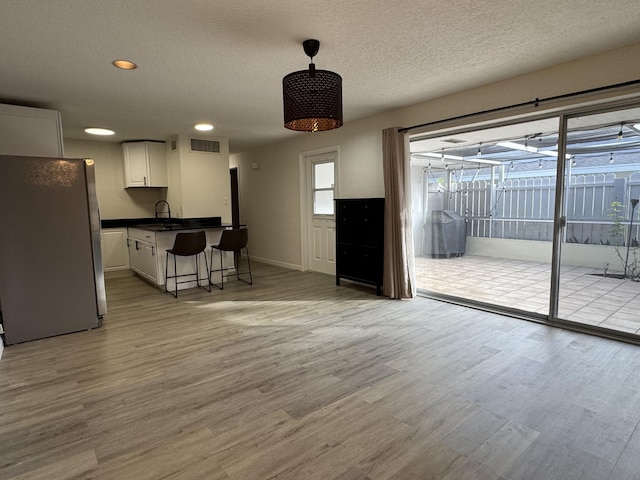 unfurnished living room with sink, a textured ceiling, and light wood-type flooring