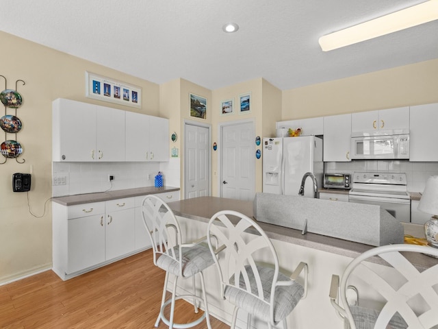 kitchen featuring white cabinets, white appliances, backsplash, and light hardwood / wood-style flooring