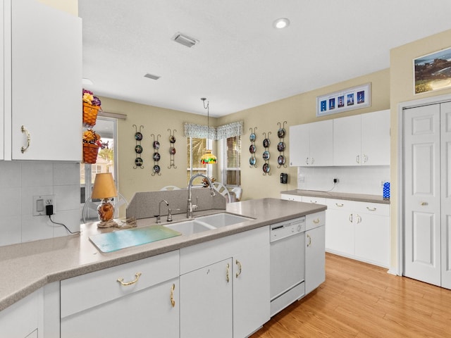 kitchen featuring white cabinetry, sink, white dishwasher, and decorative light fixtures