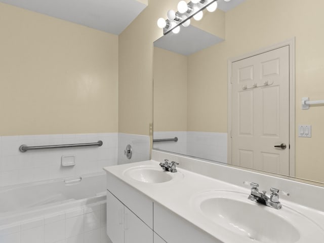 bathroom with tile patterned flooring, vanity, and tiled bath