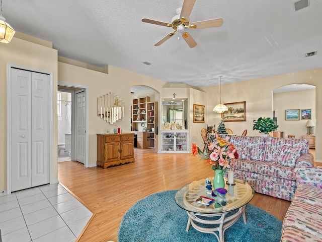 living room with ceiling fan, light hardwood / wood-style floors, and a textured ceiling