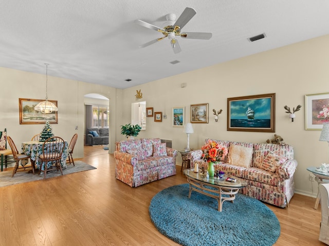 living room featuring ceiling fan, a textured ceiling, and light hardwood / wood-style flooring