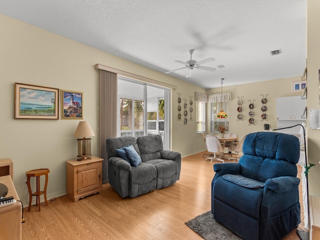 living room featuring ceiling fan, light hardwood / wood-style floors, and a textured ceiling