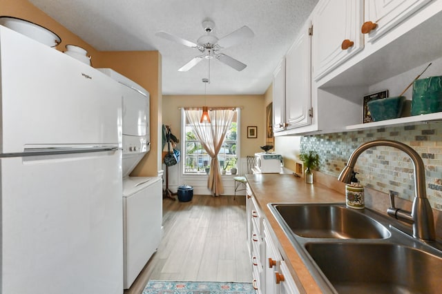 kitchen with sink, decorative light fixtures, decorative backsplash, white cabinets, and stacked washer and clothes dryer