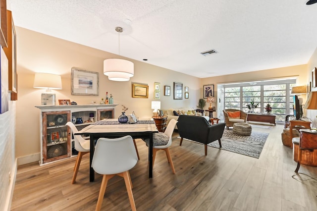 dining space featuring light hardwood / wood-style flooring and a textured ceiling