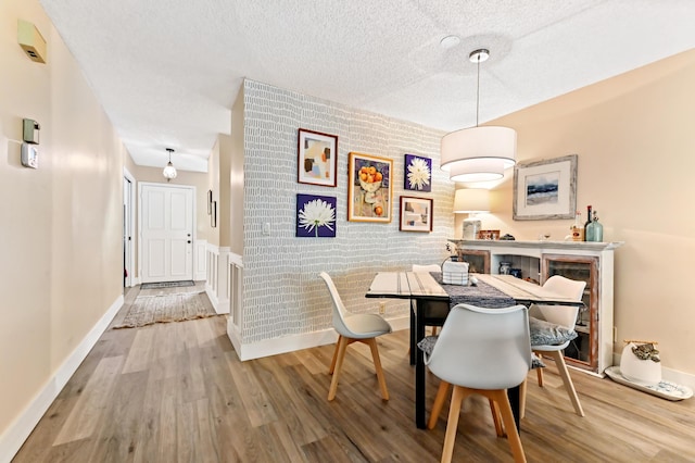 dining area with wood-type flooring and brick wall