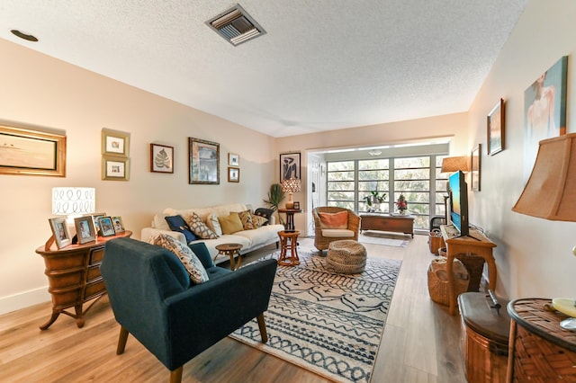 living room with light wood-type flooring and a textured ceiling