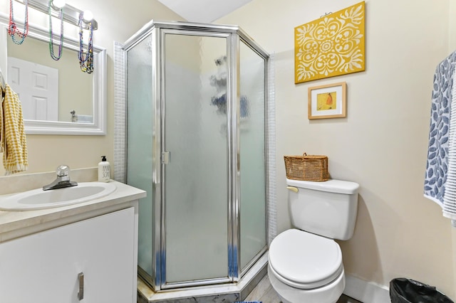 bathroom featuring vanity, a shower with shower door, and toilet