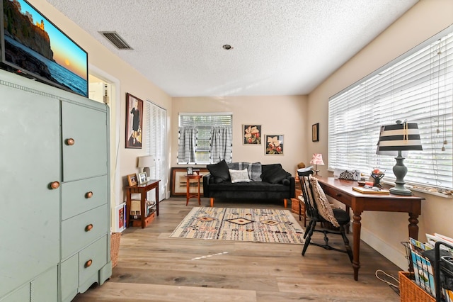 office with light hardwood / wood-style floors, a textured ceiling, and a wealth of natural light