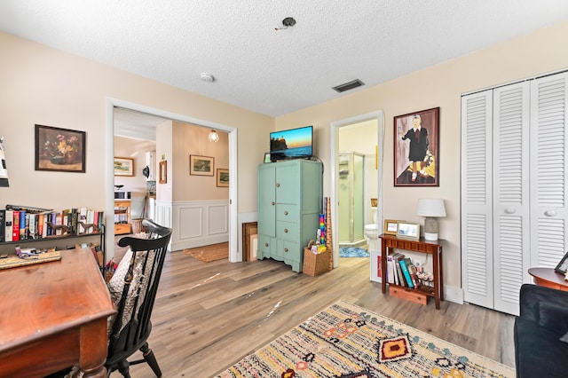 home office featuring light hardwood / wood-style flooring and a textured ceiling