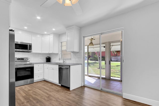 kitchen with appliances with stainless steel finishes, light hardwood / wood-style floors, and white cabinetry