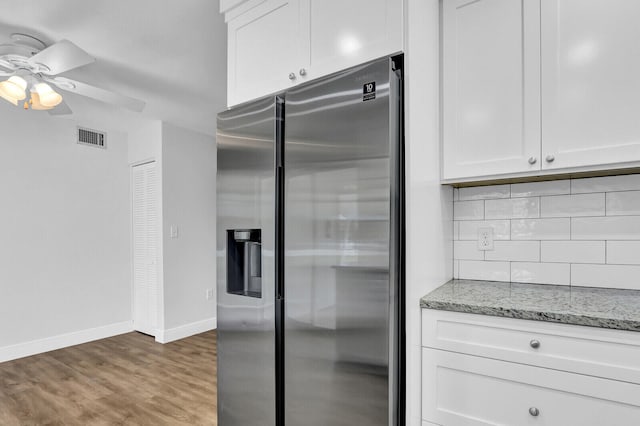 kitchen featuring white cabinets, light stone counters, and stainless steel fridge with ice dispenser