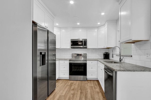 kitchen featuring appliances with stainless steel finishes, light wood-type flooring, sink, stone countertops, and white cabinets