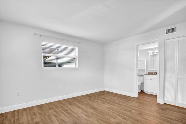 unfurnished bedroom with connected bathroom, light hardwood / wood-style flooring, and a closet