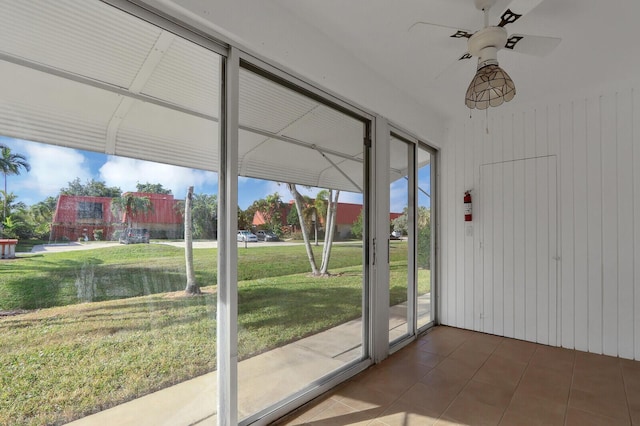 doorway featuring tile patterned floors, wood walls, and ceiling fan