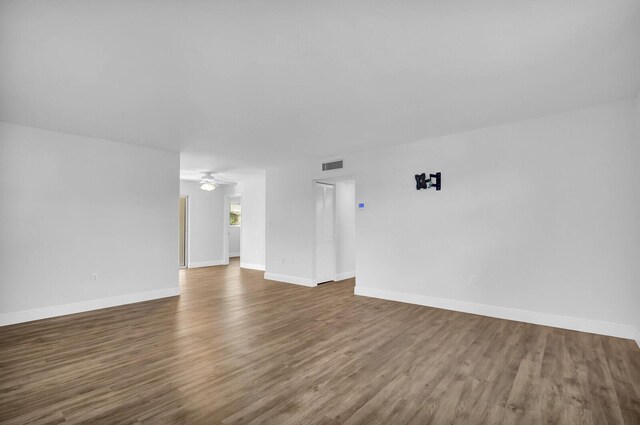 unfurnished living room featuring ceiling fan and dark wood-type flooring