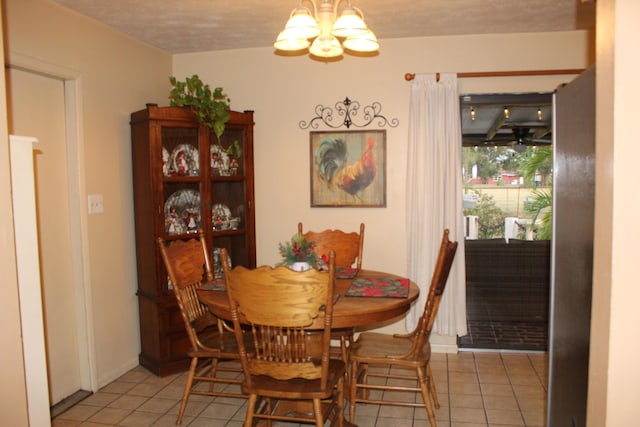 tiled dining space featuring a textured ceiling and a chandelier