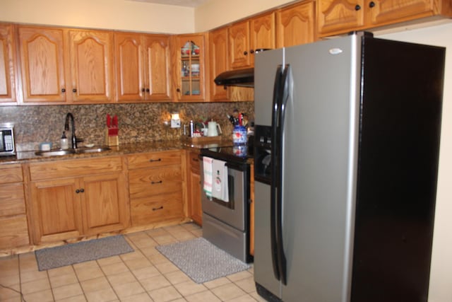 kitchen with light tile patterned flooring, sink, dark stone counters, stainless steel appliances, and backsplash