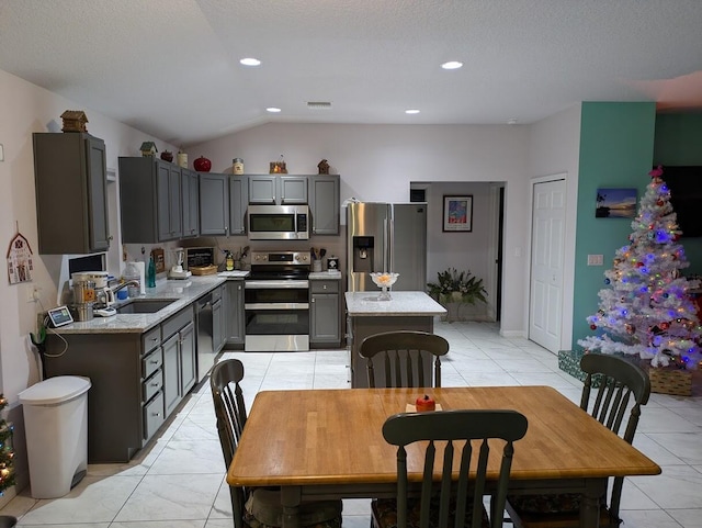 kitchen with sink, gray cabinets, stainless steel appliances, and light stone countertops