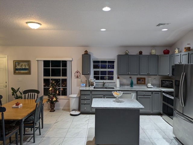 kitchen featuring gray cabinetry, light stone counters, sink, and stainless steel appliances