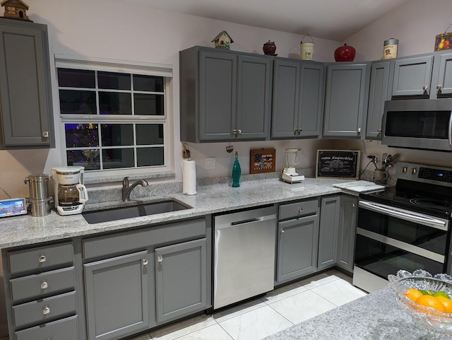 kitchen with light stone counters, sink, gray cabinets, and stainless steel appliances