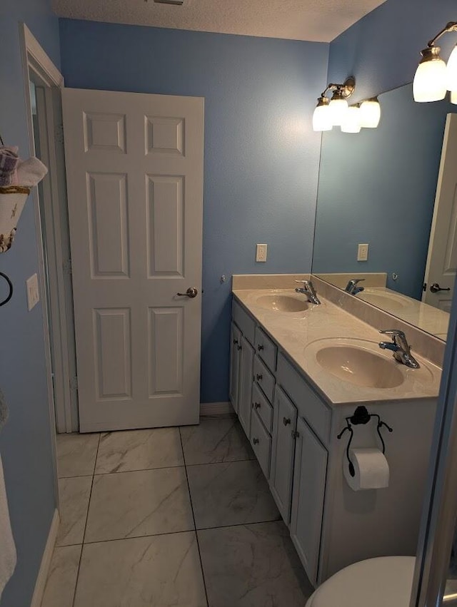 bathroom featuring vanity, toilet, and a textured ceiling