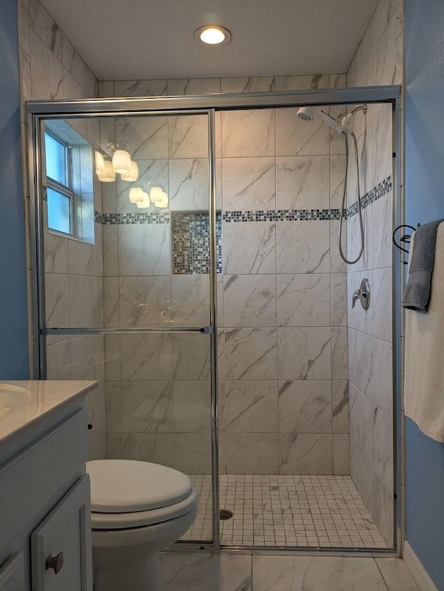 bathroom with vanity, a shower with shower door, and toilet