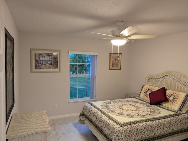 bedroom with ceiling fan and a textured ceiling