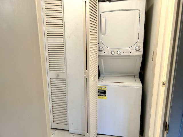 clothes washing area with stacked washer / drying machine and light tile patterned floors